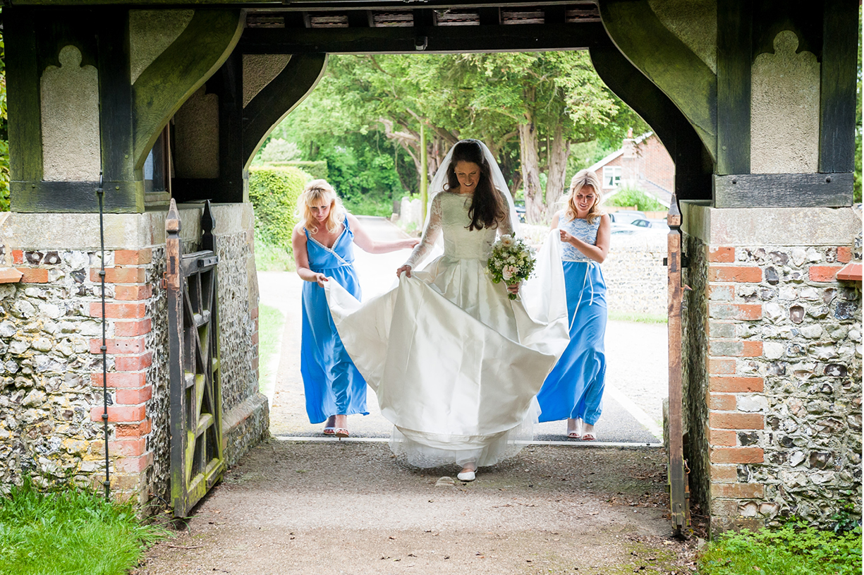 bride and maids of honour enter church gate at a Northington, Hampshire spring wedding 