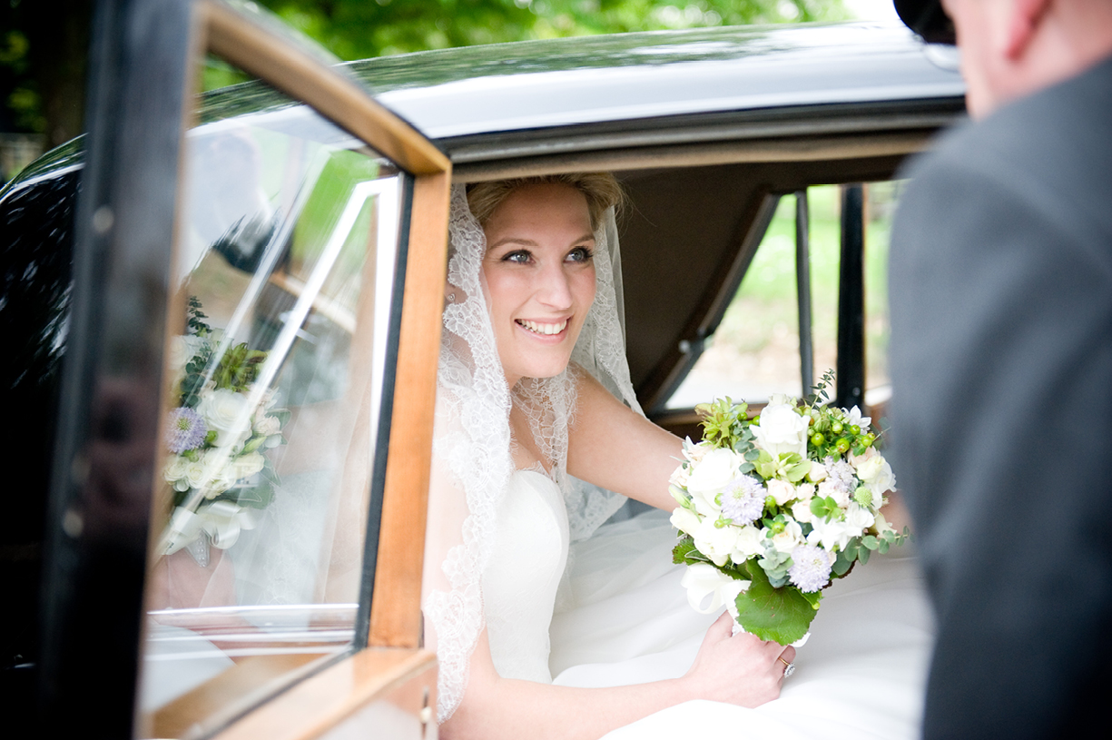 smiling bride arriving at church in Hertfordshire before reception at Munden Estates